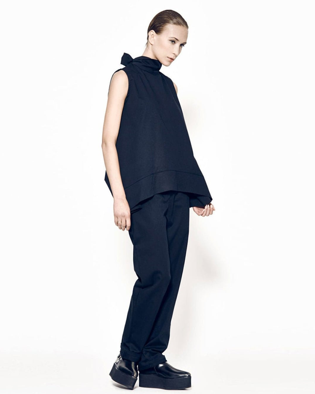 Person wearing a navy sleeveless top and pants on a white background